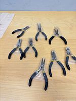 Eight individually wrapped mini pliers on tabletop