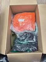 Top view of box showing orange sealed garment and dark garment beneath