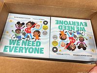 Top view into box showing stacks of We Need Everyone hardcovers