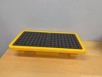 Top view of yellow tray with black perforated grate