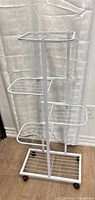 Full view of assembled white metal 4-tier plant stand on wheels