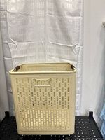 Front three-quarter view of assembled beige perforated foldable laundry basket on wheels