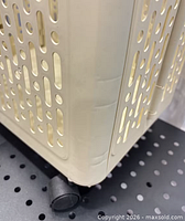 Close-up of basket corner showing perforated plastic sides and caster wheel