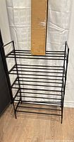 Assembled black metal shoe rack with boxed unit resting on top