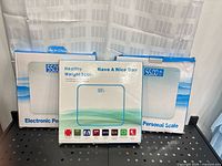 Three boxed digital bathroom scales on shelf
