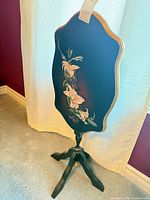 Full view of hand painted black tilt-top accent table in upright locked position