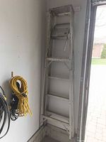 Full view of folded 6-ft aluminum ladder with tool tray mounted on wall