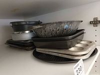 Stacked baking pans on shelf including pie, springform, rectangular and muffin pans