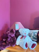Overall view of two teddy bears, needlepoint pillow and burgundy lamp