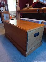 Perspective view of cedar chest next to bed showing dovetail corners and side handle