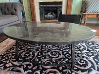 Coffee table front view showing stone top, metal frame, lower wire shelf