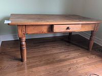 Three-quarter view of full pine table showing drawer and legs