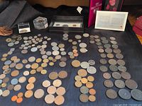 Wide view of all items including loose world coins, coin paperweight, uncirculated set box, proof set case