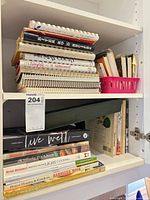 Shelf with stacked spiral and standard cookbooks, wooden stand visible