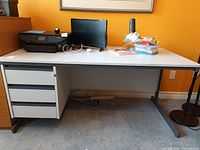 Front view of laminate office desk showing three-drawer pedestal and T-shaped legs