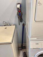 Full view of Dyson V7 vacuum on wall mount with wand and floor head