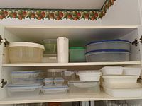 Open cabinet showing full assortment of food storage containers, salad spinner, milk jug, jello moulds