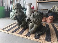 Both resin child statues on striped jute mat