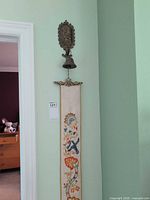 Full view of brass bell, ornate backplate and attached long tapestry bell pull