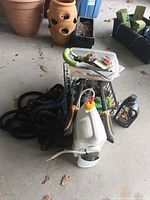 Overall view showing hose, hose fittings, lopper, Round Up jug, fertilizer jug and small tools