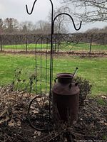 Full view of milk can, shepherd's hook, trellis in garden setting