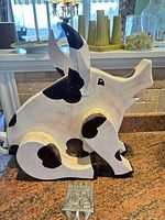 Side view of painted wooden pig and partial metal hook