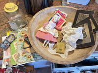 Overview of lot showing bowl, doll, jar, photographs, compact, brooch, ephemera