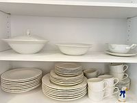 Shelved view of plates, bowls, cups, lidded bowl, open bowl, gravy boat