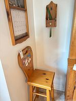 Stool, calendar holder, and wall shelf displayed in corner