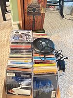 Stack of CDs with Nexxtech Discman and adapter visible