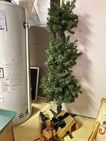 Full view of slim artificial tree with gold presents at base