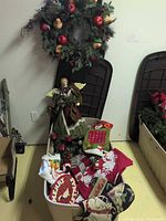 Overview of tote with angel, stockings, pillow covers, candle holder; wreath visible in background