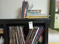 Books and magazines on shelf and stacked on top