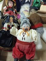 Group of dolls showing porcelain clown, female folk dolls, others in box