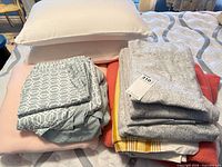 Full lot: pillows, folded sheet sets, blankets stacked