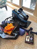 Grouping of elliptical, yoga mat, dumbbells, resistance bands, tote bag and boxed strap kit