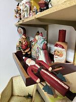 Shelf showing multiple Santa figurines, candle block and tray