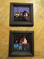 Two square framed textile artworks on tabletop