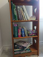 Tall wooden shelf containing multiple gardening books, notebook and bookmark