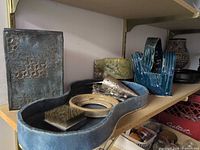 Shelf with multiple hand-thrown pottery pieces and other accessories