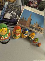Six nesting dolls in front of two hardcover books