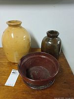 Tan vase, brown vase and red planter displayed on table