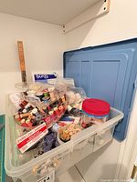 Overall view of clear bin filled with thread spools, trims, ruler, jar of buttons