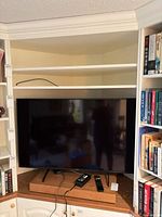 Sony Bravia 50-inch TV on shelf with stand, power cable, two remotes visible