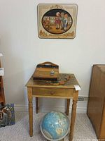 Desk, globe, wall plaque and additional plaque visible