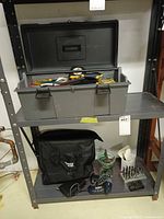 Shelf with grey toolbox open and black tool bag below