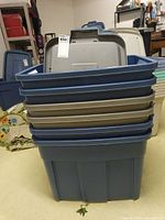 Stack of six blue Rubbermaid Roughneck totes with assorted lids
