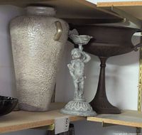 Textured glazed pottery vase, stoneware putto figurine, metal urn planter on shelf