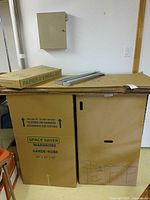 Two assembled wardrobe boxes with flattened boxes and hanger bars on top
