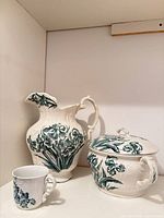Overall view of pitcher, chamber pot with lid, and mug showing matching floral pattern